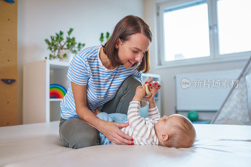 快乐的白人母亲在家里的游戏室和婴儿男孩玩