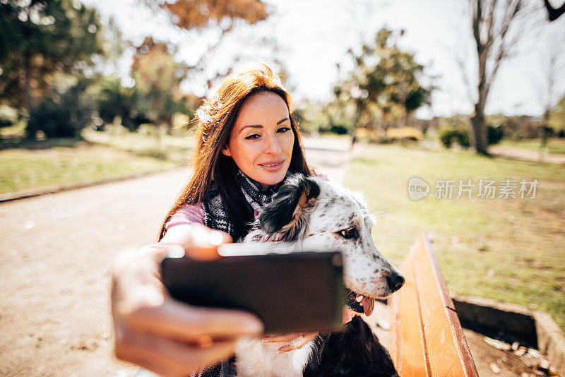 一名妇女抚摸着她的狗并自拍