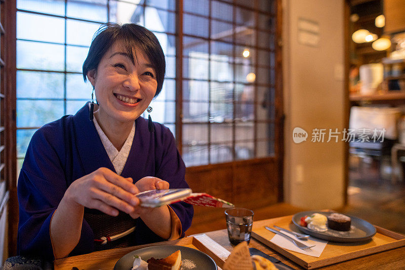 穿着和服的日本女人在日本餐厅使用智能手机