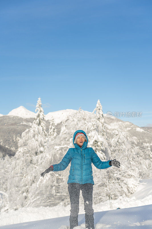 在冬天的森林里，成熟的女人穿着皮大衣向空中抛雪