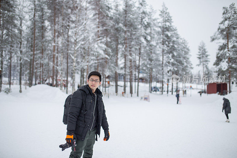 亚洲华人男性游客拿着相机在雪天的大自然中拍照