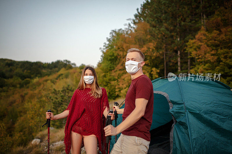 一对戴着防护面具徒步旅行的年轻夫妇