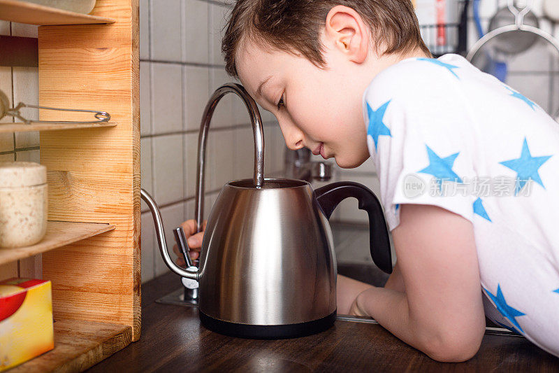 一个小男孩把水倒进壶里。家里的生活方式。