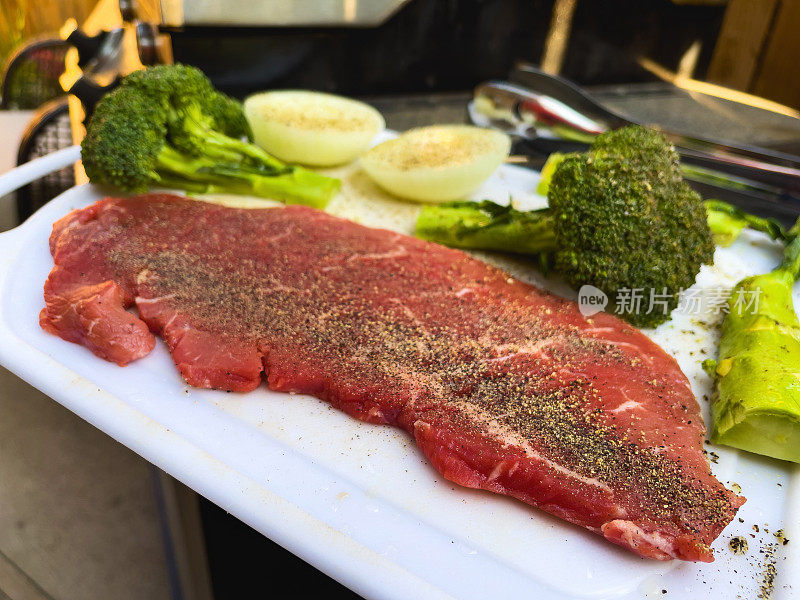 户外烧烤牛肉牛腰牛排西兰花和洋葱生在砧板烤照片系列