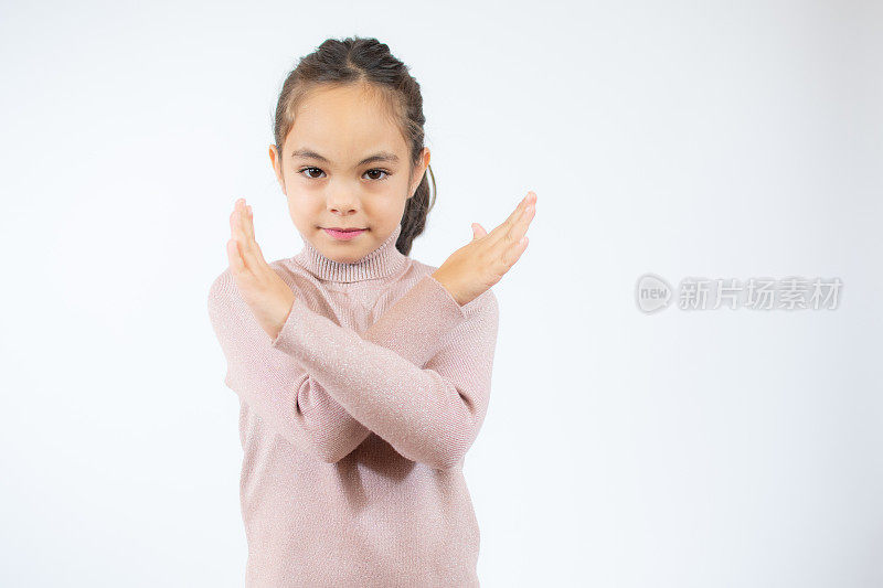 白色背景下的小女孩有拒绝的表情，交叉双臂和手掌做否定的手势，愤怒的脸。