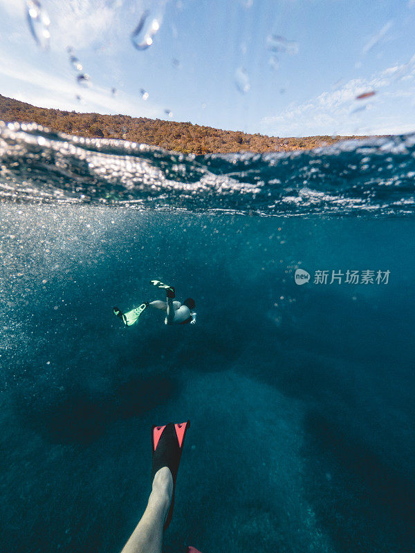 一对夫妇带着面具和潜水脚蹼在水下游泳