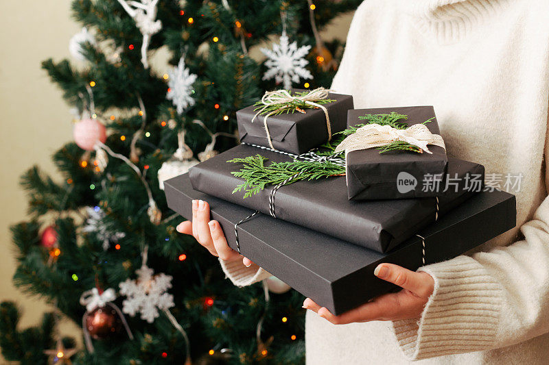 女孩手里拿着一堆礼物盒子。在背景上装饰圣诞树