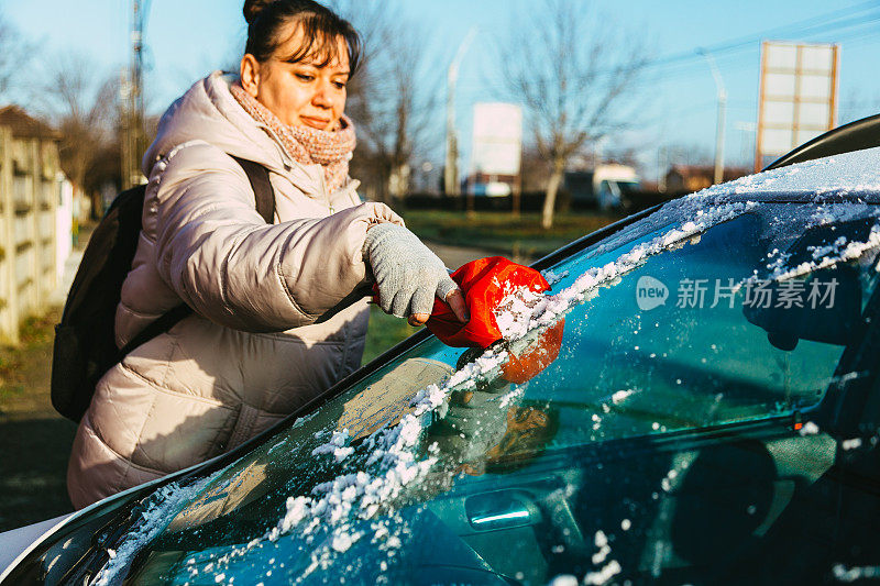 冬天的早晨，一位妇女从车上刮冰