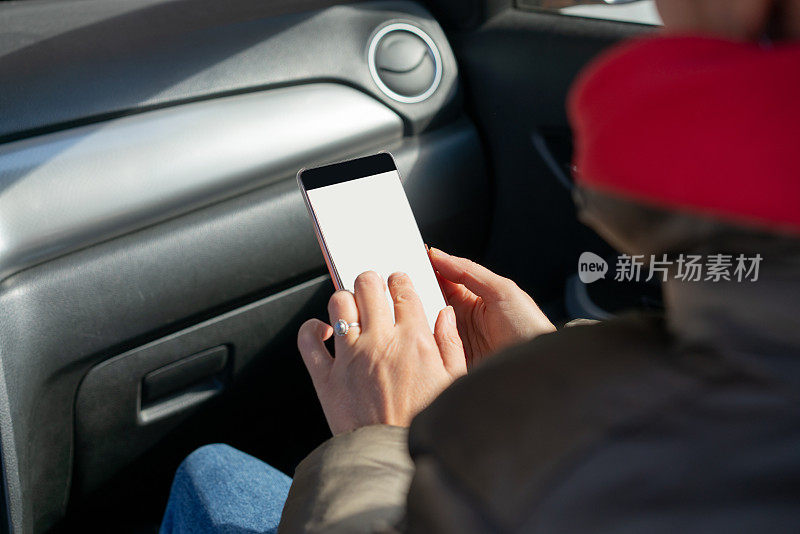 女人在车里手拿智能手机。