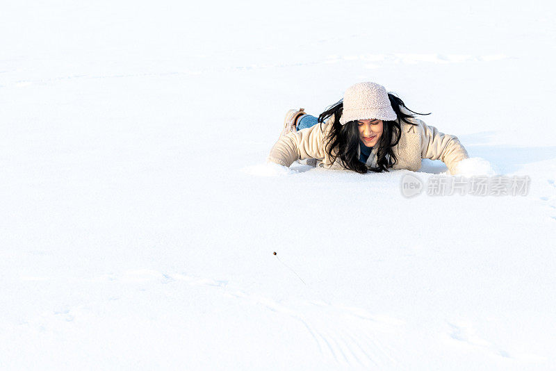 年轻女子在冬天的雪地里玩得很开心