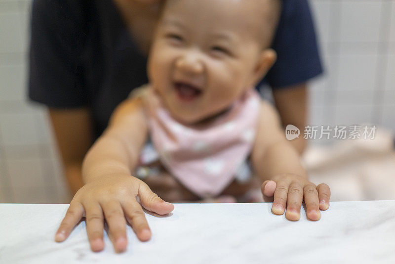 微笑的亚洲婴儿玩她的手指