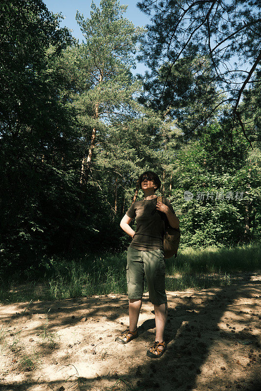 一位女背包客正在森林中徒步旅行