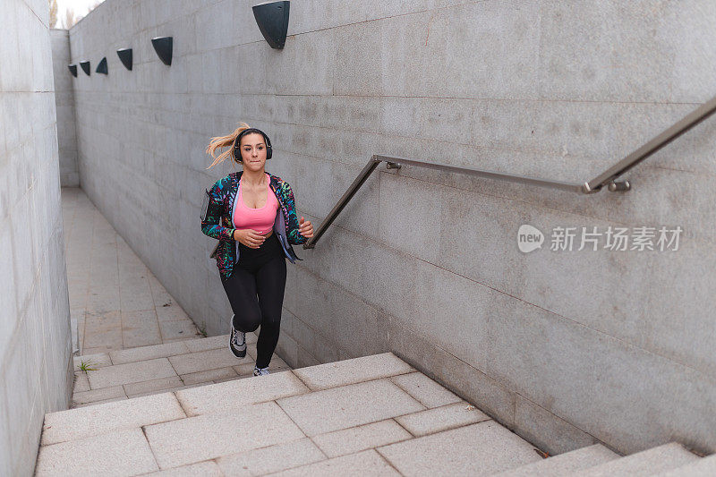 健身年轻女运动员在城市环境中跑步上楼梯