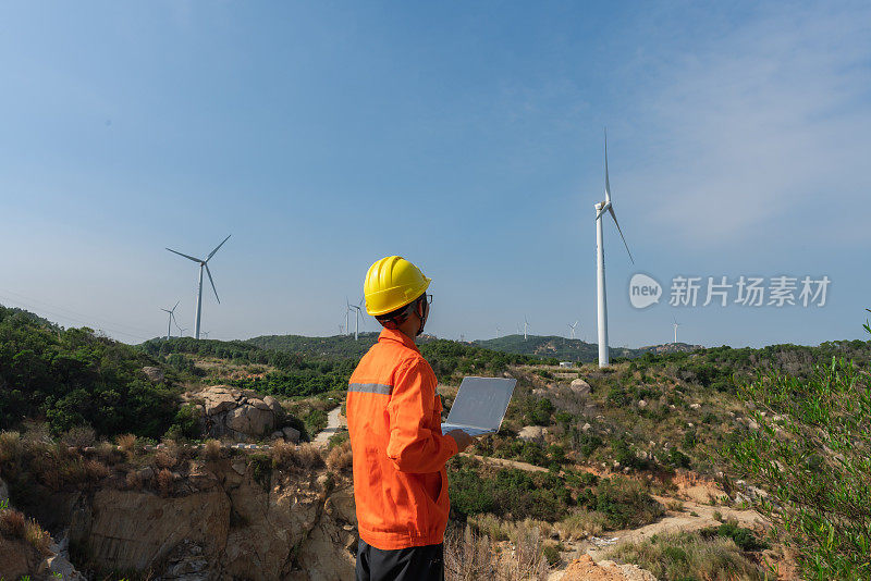 工程师在风力发电场使用笔记本电脑