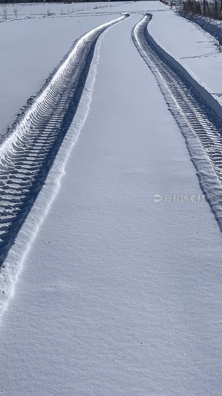 阳光下乡间白雪上的轮胎印