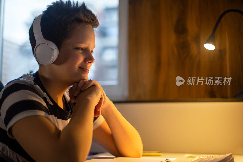 一个十几岁的男孩正在参加一个在线课程并做笔记。