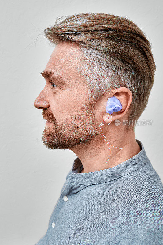 男性患者在听力学诊所根据自己的耳朵形状制作助听器的耳模。定制入耳模具