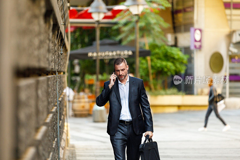 一个穿着西装的年轻帅哥正赶着去上班，手里拿着他的智能手机。