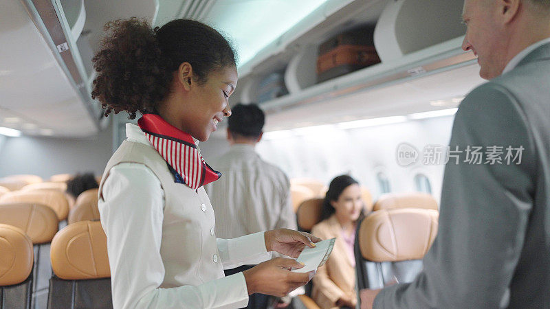 女空姐在飞机上迎接乘客，并检查乘客的登机牌，欢迎乘客登机。航空公司运输