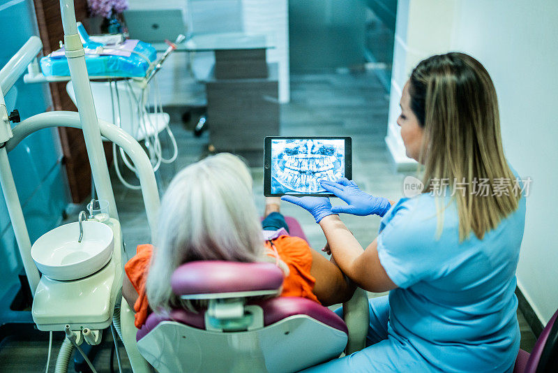 牙医在诊所里给一个成熟的女人看x光片