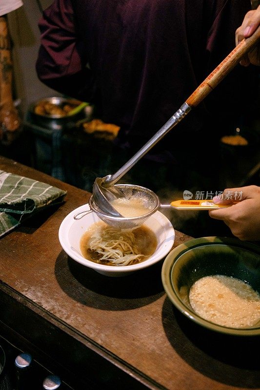 厨师用自制的酱料准备一碗拉面