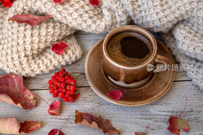 秋天的心情，秋天的背景。一杯咖啡，木底上织着秋叶和浆果的围巾。