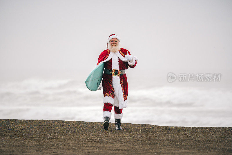 沙滩上的圣诞老人拿着冲浪板