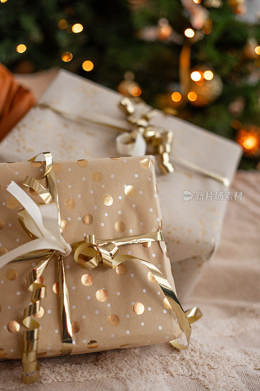 圣诞树下有金色包装纸和彩带的圣诞礼物