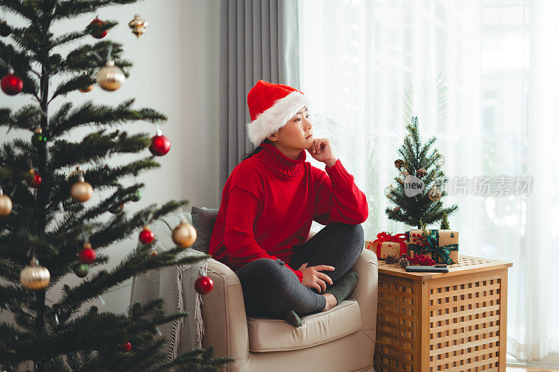亚洲女人感到孤独，独自坐在圣诞节思考问题。