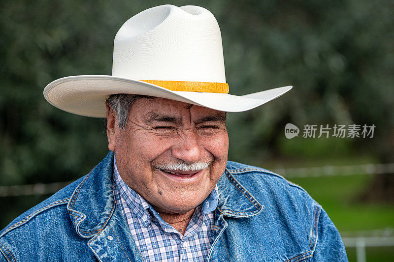 一个面带微笑的西班牙裔老人，头戴牛仔帽，望向别处