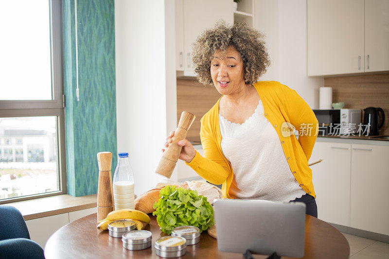 快乐的成熟女人正在厨房里准备一顿健康的饭菜