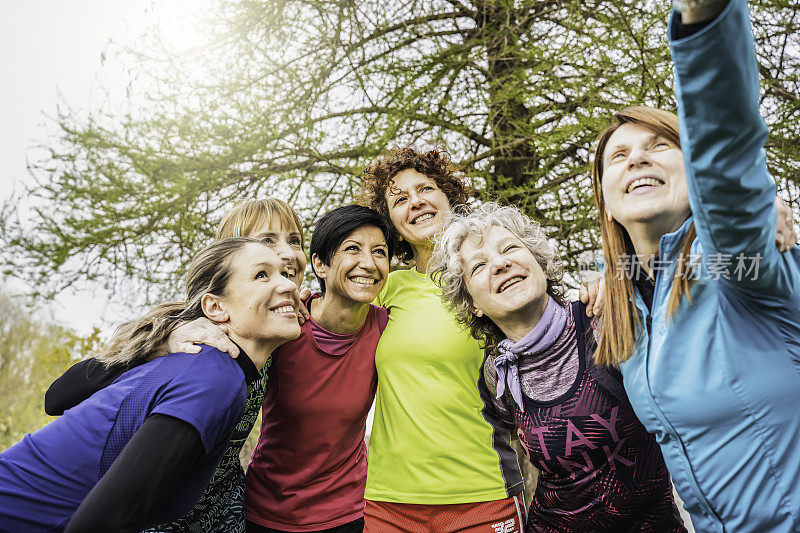 一群充满活力的女人在公园里享受一天。朋友们分享快乐的自拍，反映了一种积极的、多代人的生活方式——女性的健康生活方式概念