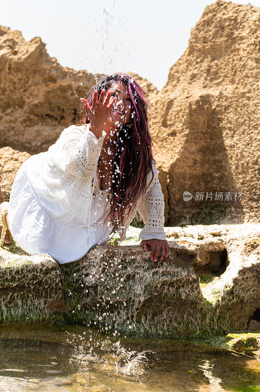 女人跪在岩石上玩海水