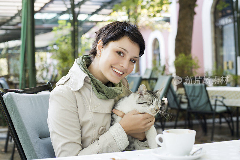 一个女人抱着猫在外面喝咖啡