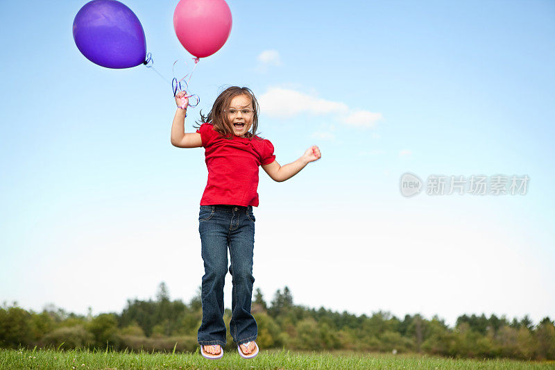 小女孩拿着气球在外面跳