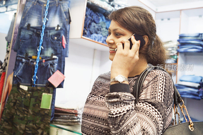 年轻的印度女人在购物中心用智能手机聊天