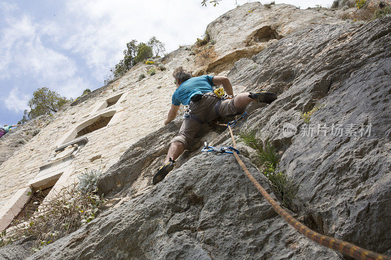 攀岩者攀登垂直悬崖下的石头住所