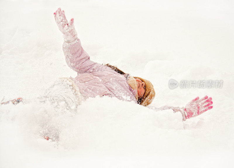 小女孩高兴地在雪地里打滚