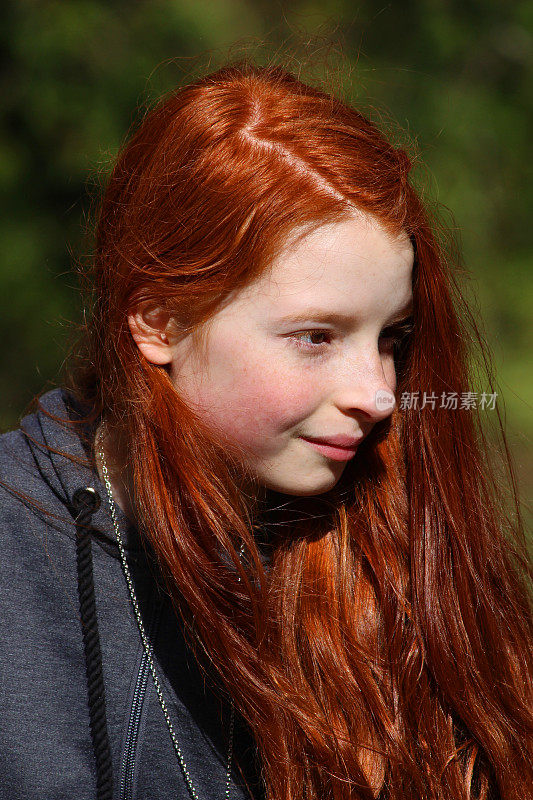 长着一头红发的漂亮女孩坐在户外