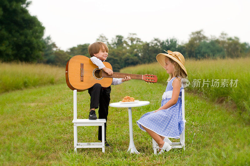 小男孩拿着吉他唱着小夜曲，小女孩坐在桌旁