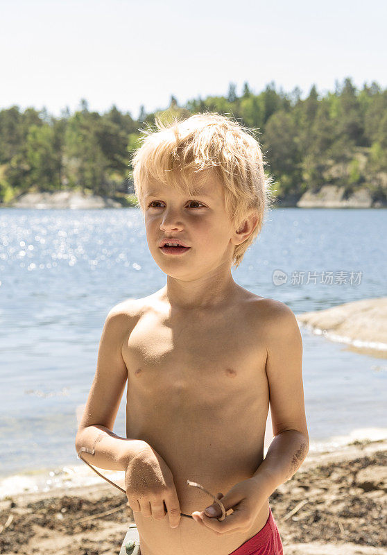 一个金发小男孩在斯德哥尔摩群岛的海滩上玩耍