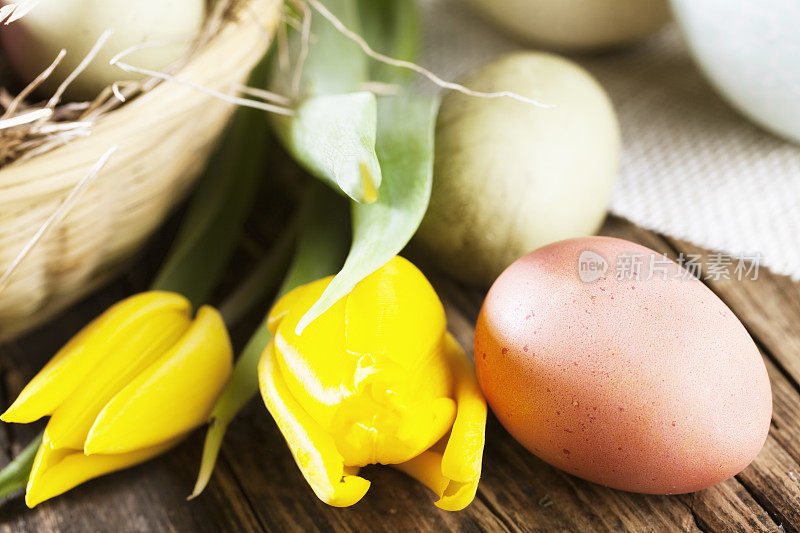 传统的复活节彩蛋和黄色郁金香放在木头上