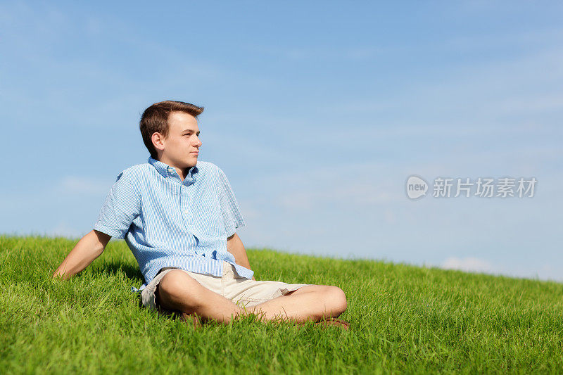 坐在户外草地上展望未来的年轻人