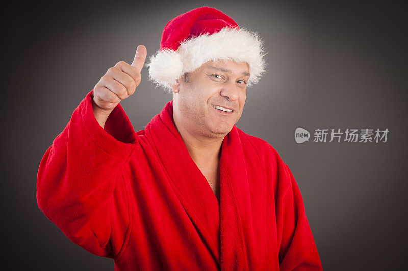 快乐的男人戴着圣诞帽，竖起大拇指