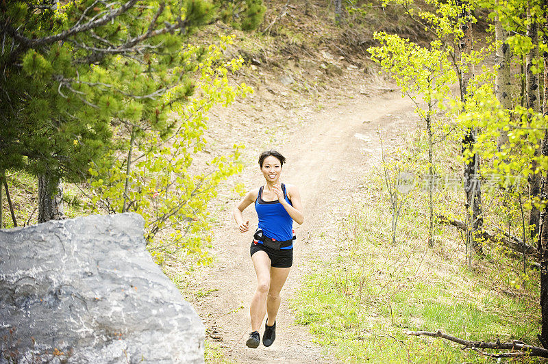 亚洲妇女在落基山脉，阿尔伯塔，加拿大Trail跑步。