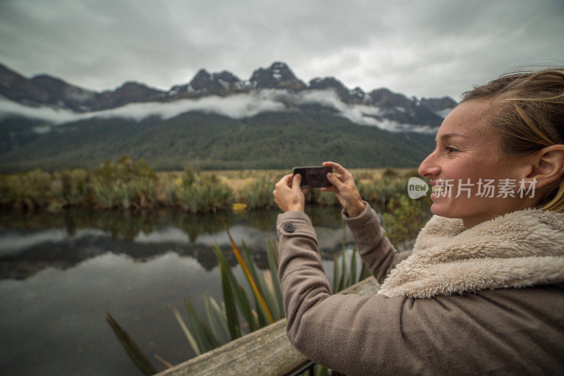 年轻女子用智能手机拍摄山景