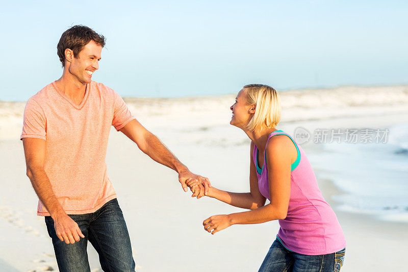 好玩的女人在海滩上拉着男人的手