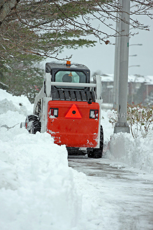 迷你前端装载机清除雪从一个城市的人行道