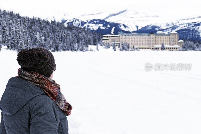 一个白人妇女的后视图与冬天的衣服，看着费尔蒙特城堡湖路易丝，班夫国家公园，阿尔伯塔，加拿大