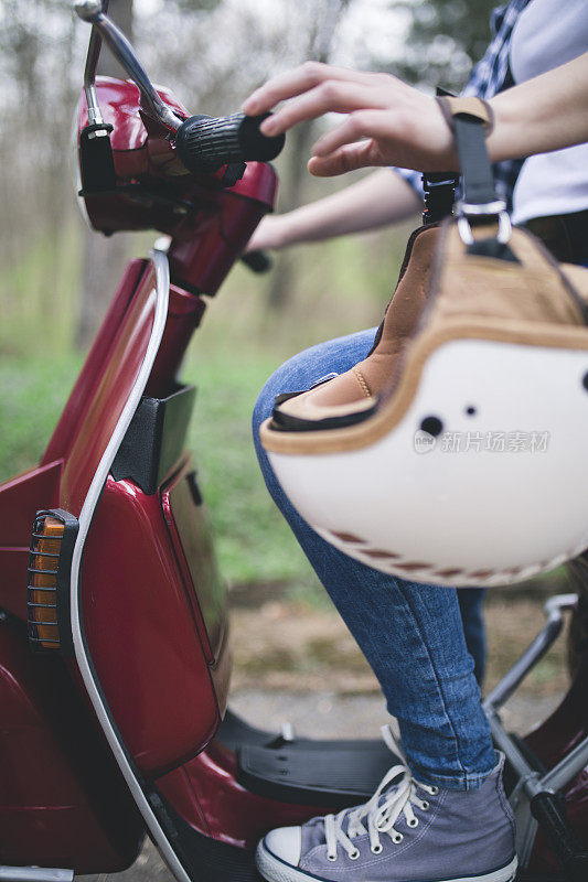 戴着头盔坐在老式摩托车上的年轻时髦女人。